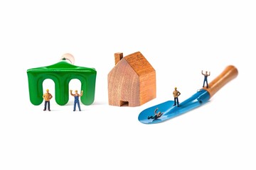 wood house and garden tool with miniature worker isolated on white background.