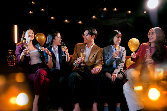 Beautiful woman having fun with group of friends clinking champagne glasses during celebration party. Drink concept.