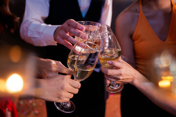 Beautiful woman having fun with group of friends clinking champagne glasses during celebration party. Drink concept.