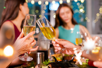  Beautiful woman having fun with group of friends clinking champagne glasses during celebration party. Drink concept.