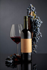  Red wine with a weathered snag and blue grapes on a black background.