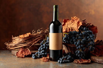 Bottle of red wine with blue grapes on a brown background.