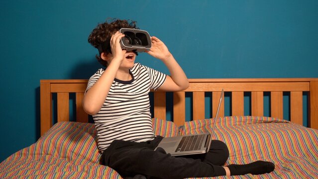 Little boy Immersed in cyberspace, metaverse, learning in virtual reality. Kid playing games. Child learning using virtual reality headset. Education child in virtual reality glasses. laptop and globe
