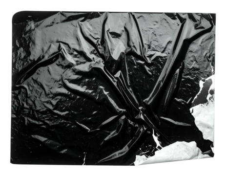 Glossy, crinkled black surface with tear, revealing white
