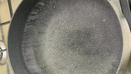 A pot of boiling water on a stove, bubbles forming and rising, kitchen activity and cooking preparation, culinary process and home cooking theme