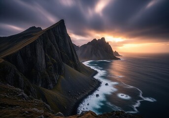 Rugged coastal mountain range meets turbulent ocean waves at a dramatic stormy sunset