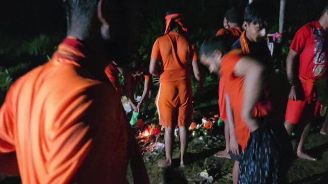 Authentic documentary footage of Kanwariya devotees gathering at a riverbank during the sacred Kanwar Yatra in India. Wearing traditional saffron clothing and carrying decorated Kanwars