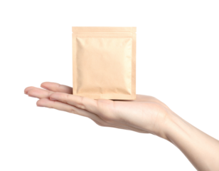 A hand holding a small, square kraft paper pouch with a zipper closure, isolated on black