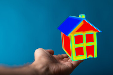 Conceptual image of a person holding a colorful house model, representing home ownership, real estate, and concepts like energy efficiency, with