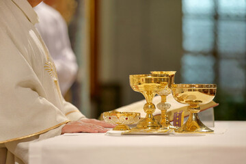 Chalices in the hands of the priest on the altar during the celebration of the mass