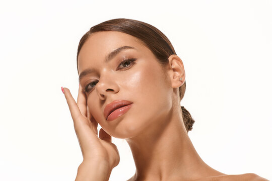 Fototapeta Young woman displays natural beauty with subtle makeup against a white canvas