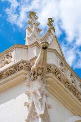 Close-up on white gargoyle standing on the top of historic french building