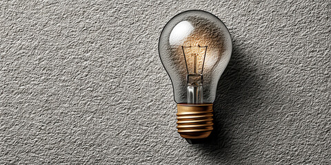 Illuminated Light Bulb with Gold Base on a Textured Gray Surface