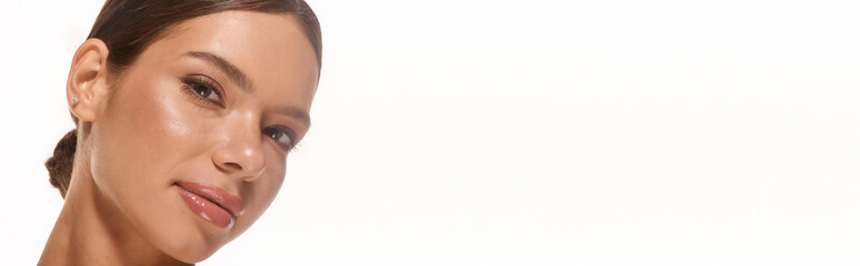 Obraz premium Captivating young woman with natural makeup glowing against a plain backdrop