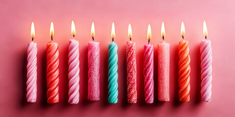 Row of Colorful Lit Birthday Candles on Pink Background