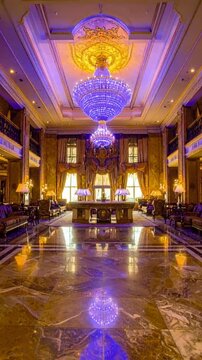 Ornate Hotel Lobby With Grand Chandeliers And Marble Flooring Illuminated By Warm Light