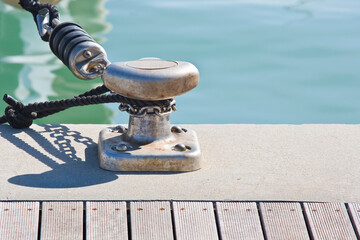 Metal cleat for mooring boats, bolted to the ground, with rope and shock absorber
