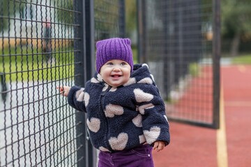 Happy baby girl in winter clothes smiling outdoors. Development milestones