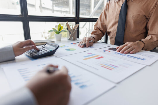 Group of confident business people point to graphs and charts to analyze market data, balance sheet, account, net profit to plan new sales strategies to increase production capacity.	