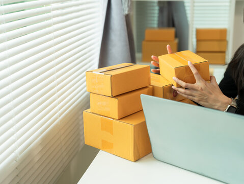 Asian SME businesswoman working in home office, checking customer orders on online marketplace, preparing to box and sell to customers, SME business idea, close up.