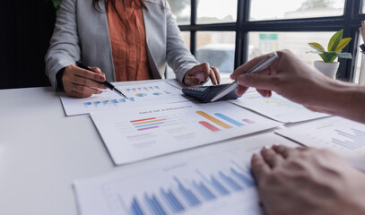 Group of confident business people point to graphs and charts to analyze market data, balance sheet, account, net profit to plan new sales strategies to increase production capacity.	