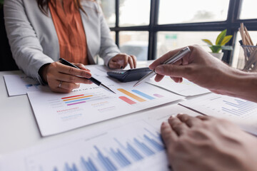 Group of confident business people point to graphs and charts to analyze market data, balance sheet, account, net profit to plan new sales strategies to increase production capacity.	