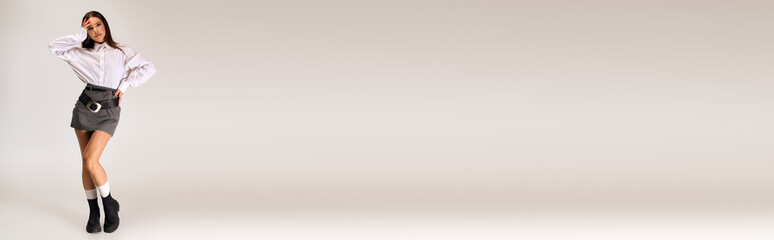 Stylish young woman showcases autumn fashion in a chic grey studio setting