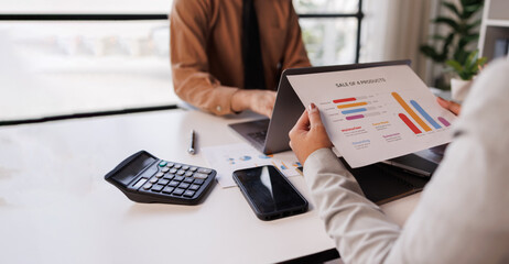 Business team deeply engaged in a meeting, analyzing financial data with a tablet and paperwork adorned with various graphs and charts. Technology aids in decision-making for business growth
