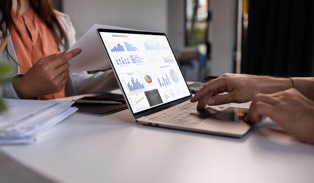 Business team deeply engaged in a meeting, analyzing financial data with a tablet and paperwork adorned with various graphs and charts. Technology aids in decision-making for business growth
