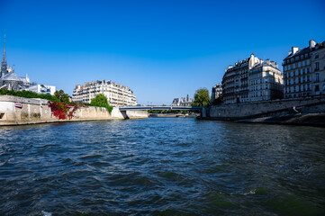 Scenic view of a river flowing between historic buildings under a clear blue sky, showcasing urban architecture and natural beauty