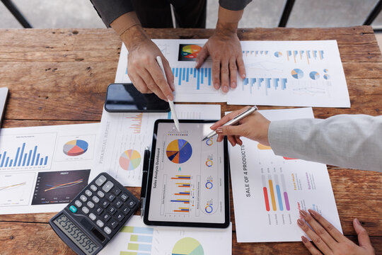 Two colleagues engaged in business analytics, using digital tablets over financial charts. Colleagues Collaborating with Tablets on Business Analytics.

