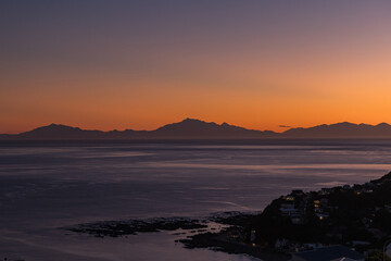 ニュージーランド　ウェリントンのアイランド・ベイから見えるクック海峡と南島の山々と夕焼け空