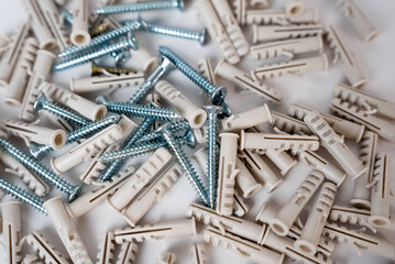 Close-up of a pile of metallic screws and plastic wall plugs. Great for hardware, building, or DIY...