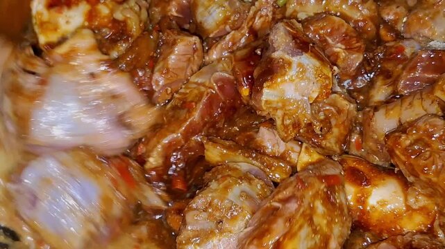 Marinated beef simmering in sweet soy sauce and spices as a cook gently stirs the mixture to prepare traditional Semur Daging.