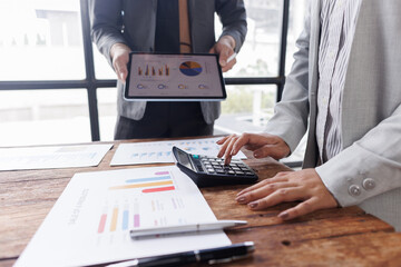 Colleagues engaged in business team analytics, using digital tablets over financial charts. Colleagues Collaborating with Tablets on Business Analytics.
