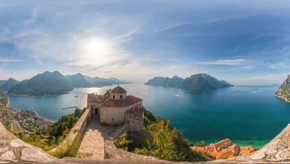 Circular perspective of a church overlooking a coastal town and hills during summer, featuring travel, nature, urban scenery, structures, ocean, mountains, and architecture