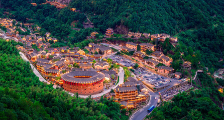 Traditional round earth building and historic village illuminated in a forest at dusk.