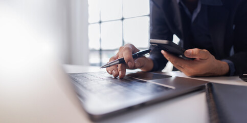 Business man pen in hand and mobile phone, online working at office. Student studying online, surfing the internet, searching the information, e-learning, business technology

