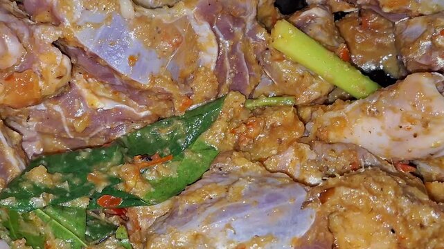 A cook stirs raw beef chunks in a hot pan with aromatic spices while preparing Semur Daging, a classic Indonesian stew.