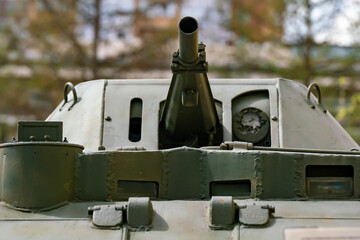 A green tank turret with a gun against the backdrop of a city.