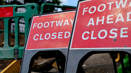 Close-up of bright red 'Footway Closed' and 'Footway Ahead Closed' signs at a construction site, useful for public works, safety, or detour concepts