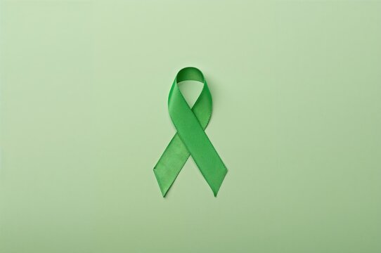 Green ribbon against a leafy backdrop symbolizing mental health, depression, and cerebral palsy awareness. Overhead perspective with ample space for text. - Powered by Adobe