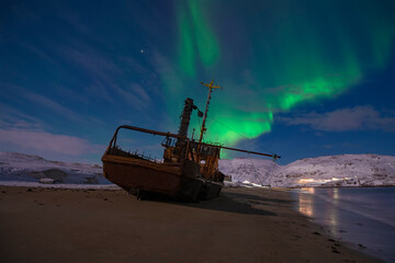 Aurora borealis over an old abandoned ship on a March night. Teriberka. Murmansk region, Russia