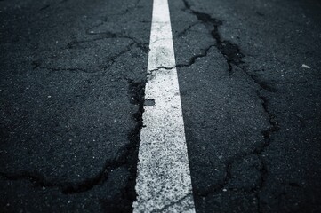 Obraz premium Grungy black asphalt featuring a worn white line, textured road surface, and vintage street aesthetic