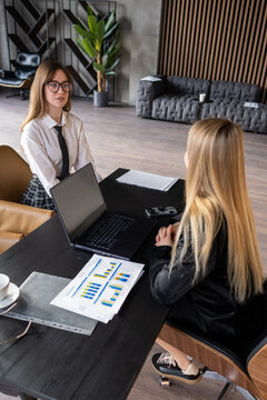 Young woman in formal wear sitting at a desk having an important job interview or business meeting with an unseen interviewer, discussing career opportunities and potential employment
