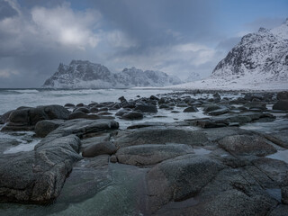 Arctic Seascape with Snow-Covered Mountains and Frozen Rocks on Lofoten Coast under Dramatic Winter Sky in Northern Norway