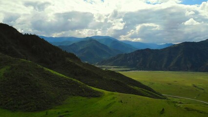 Clouds casting shadows on green mountain landscape. Media