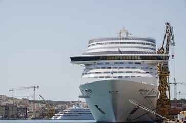 Modern cruise ship cruiseship liner Divina and Magnifica being modernized over-hauled repaired refitted maintenanced by shipyard in Malta with dock and cranes	