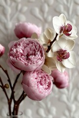 Beautiful pink peonies and white orchids arranged in a vase against a textured background