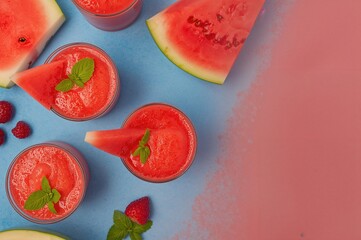 Naklejka premium Refreshing watermelon and mint beverage served in glasses on a vibrant blue surface, overhead perspective with empty space for text. Sweet seasonal smoothie, cleansing drink, natural nutritious treat.